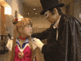 a man in a top hat and mask is touching a woman 's arm