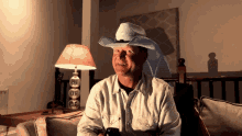 a man wearing a cowboy hat sits on a couch