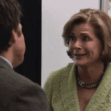 a woman in a green jacket talks to a man