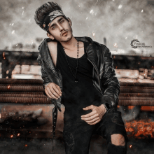 a young man wearing a black leather jacket and a black tank top is standing in front of a fire
