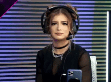 a woman wearing headphones and a choker is sitting in front of a phone .