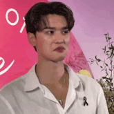 a man wearing a white shirt and a necklace with a black ribbon on his chest