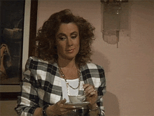 a woman in a plaid jacket is drinking a cup of tea