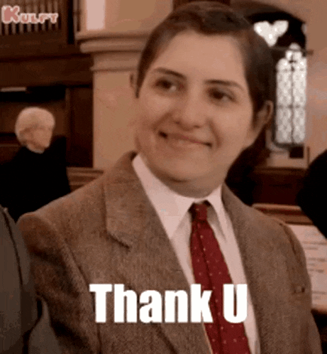 a woman wearing a suit and tie is smiling and saying thank u