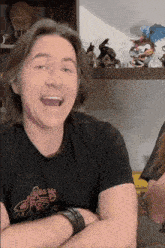 a man with long hair is wearing a black shirt that says ' flex ' on it .