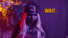 a woman with blood on her face is wearing a black shirt that says " wait what "