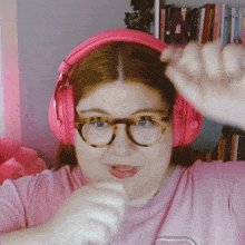 a woman wearing glasses and pink headphones is making a face