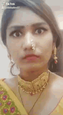a woman wearing a nose ring and a necklace is making a face .