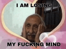an elderly man is covering his ears in front of a heart .