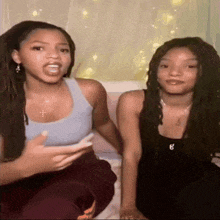 two girls are sitting next to each other with one wearing a necklace with the letter e on it