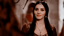 a woman with long dark hair is wearing a necklace and a headpiece .