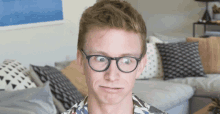 a man wearing glasses is making a funny face in a living room