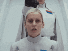 a woman in a white uniform with a blue and red badge on her chest