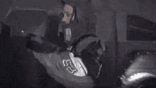 a man in a hoodie is standing in front of a van holding a knife .