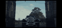 a car with a license plate that says devil is parked in front of a gate