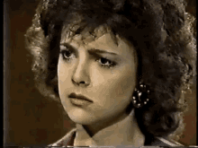 a close up of a woman 's face with curly hair and earrings