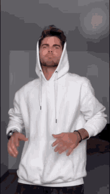 a man is wearing a white hoodie and making a funny face