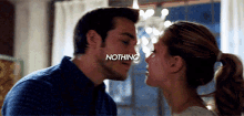 a man and a woman are kissing with the word nothing written on the man 's face