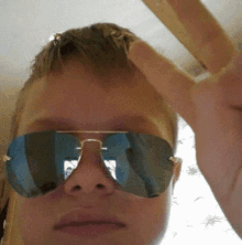 a young boy wearing sunglasses is giving a middle finger