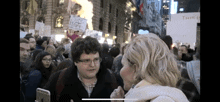a woman talks to a man holding a sign that says " climate change stops "