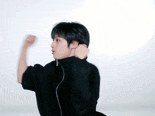 a young man in a black jacket is flexing his arm