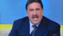a man in a suit and tie with a mustache is making a face