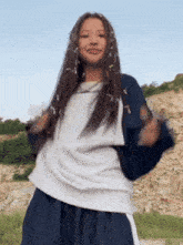 a girl with dreadlocks is dancing in front of a rock formation