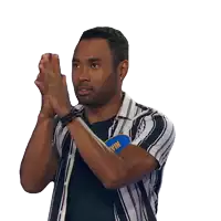 a man in a striped shirt is clapping his hands with a blue pin on his shirt
