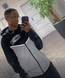 a man taking a picture of himself in front of a potted plant