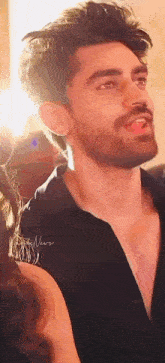 a close up of a man with a beard wearing a black shirt with his tongue hanging out .