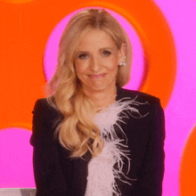 a blonde woman wearing a black jacket with feathers on the sleeves