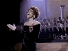 a woman is singing into a microphone in front of a choir .