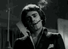a man in a suit smoking a cigarette in a black and white photo
