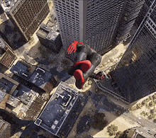 an aerial view of a city with a person in a spiderman suit flying through the air