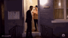 a man and a woman are standing in front of a house at night .