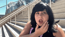 a woman with a ring on her finger is standing in front of a set of stairs