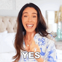a woman in a blue and white shirt is smiling with the word yes above her
