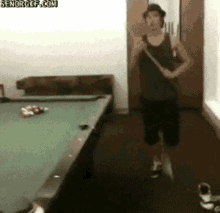 a man is standing in front of a pool table with the website senorgif.com visible in the corner