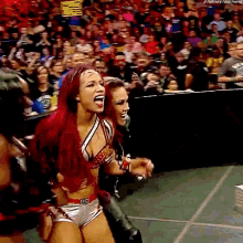 a woman with red hair is screaming in front of a crowd at a wrestling event .