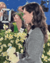 a woman holding a stuffed animal stands in front of flowers and a microphone that says wp on it