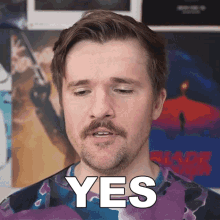a man with a beard says yes in front of a poster of blade runner