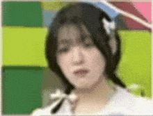 a close up of a woman 's face with a green background and a white bow in her hair .
