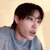 a close up of a person 's face with their mouth open and a gray shirt on .