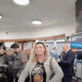 a woman wearing a t-shirt that says be cool stands in a crowded room