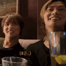 two men are sitting next to each other and one of them is holding a glass of water