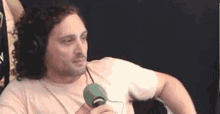 a man wearing headphones is holding a green microphone .