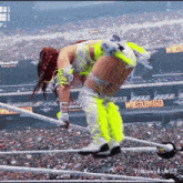 a female wrestler in a neon outfit is in the ring at wrestlemania