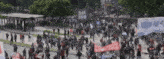 a large crowd of people are gathered in a park with a sign that says " alianza "