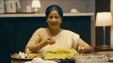 a woman is sitting at a table with plates of food on it