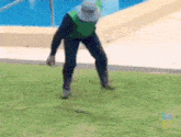 a man is kneeling down on a lush green field with big up written on the bottom right corner
